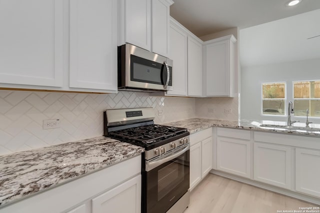 142 Ashley Loop, San Antonio, TX 78253 - kitchen with stainless steel appliances, white cabinets, light stone counters, tasteful backsplash, and light wood-style flooring