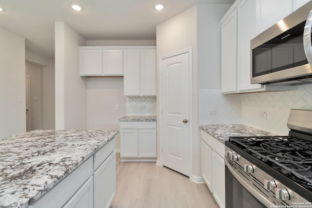 142 Ashley Loop, San Antonio, TX 78253 - kitchen featuring stainless steel appliances, light wood-type flooring, white cabinetry, recessed lighting, and light stone countertops