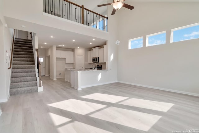 142 Ashley Loop, San Antonio, TX 78253 - unfurnished living room with light wood-style floors, stairway, ceiling fan, plenty of natural light, and a high ceiling