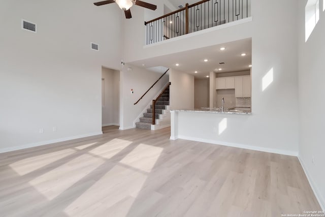 142 Ashley Loop, San Antonio, TX 78253 - unfurnished living room with a towering ceiling, a ceiling fan, light wood-type flooring, and stairway