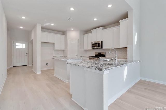 142 Ashley Loop, San Antonio, TX 78253 - kitchen featuring appliances with stainless steel finishes, light wood-style flooring, light stone countertops, white cabinets, and recessed lighting