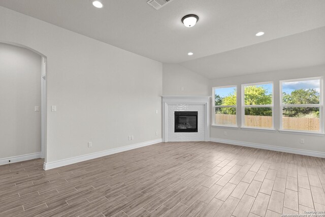 11423 Buffalo Bill, San Antonio, TX 78254 - unfurnished living room featuring wood finished floors, vaulted ceiling, recessed lighting, a tiled fireplace, and arched walkways