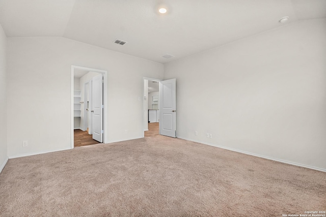 unfurnished bedroom with carpet flooring, lofted ceiling, a spacious closet, and a closet