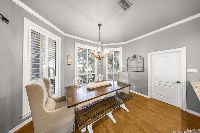 dining room with hardwood / wood-style floors, crown molding, and a notable chandelier