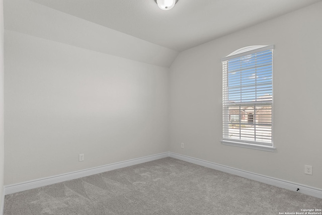 carpeted empty room featuring vaulted ceiling