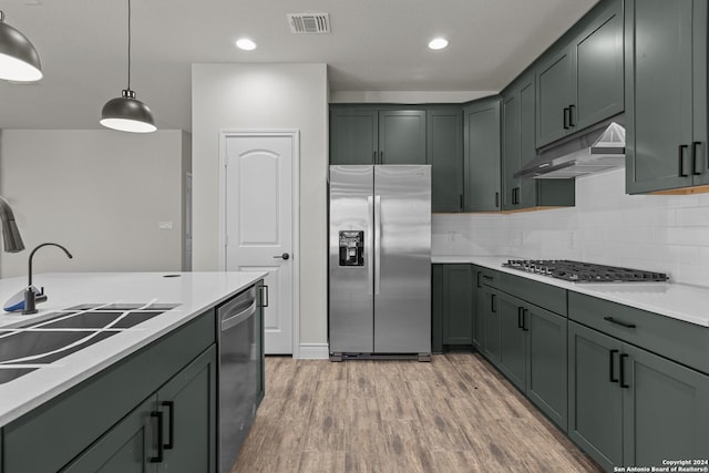 kitchen with pendant lighting, sink, appliances with stainless steel finishes, tasteful backsplash, and light hardwood / wood-style floors