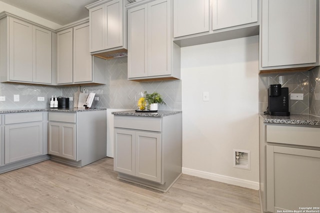 kitchen with light wood-type flooring, backsplash, and stone countertops