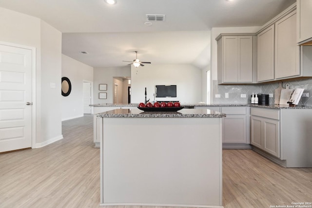 kitchen featuring gray cabinetry, light wood-type flooring, and tasteful backsplash