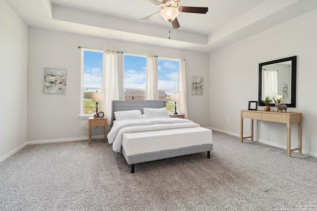 bedroom with carpet flooring, a tray ceiling, and ceiling fan