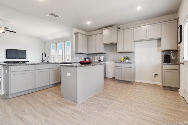 kitchen featuring gray cabinets, decorative backsplash, a kitchen island, and light hardwood / wood-style floors