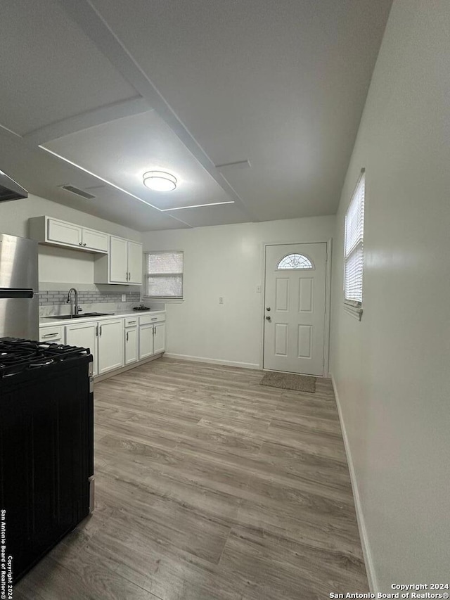 kitchen featuring white cabinets, stainless steel fridge, light wood-type flooring, and sink