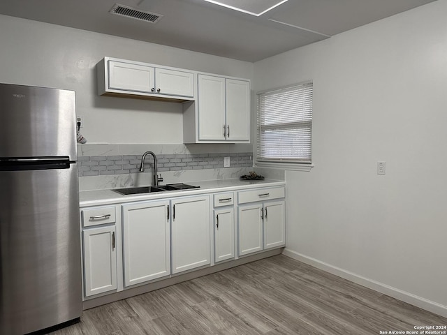 kitchen with stainless steel refrigerator, sink, white cabinets, and light hardwood / wood-style floors