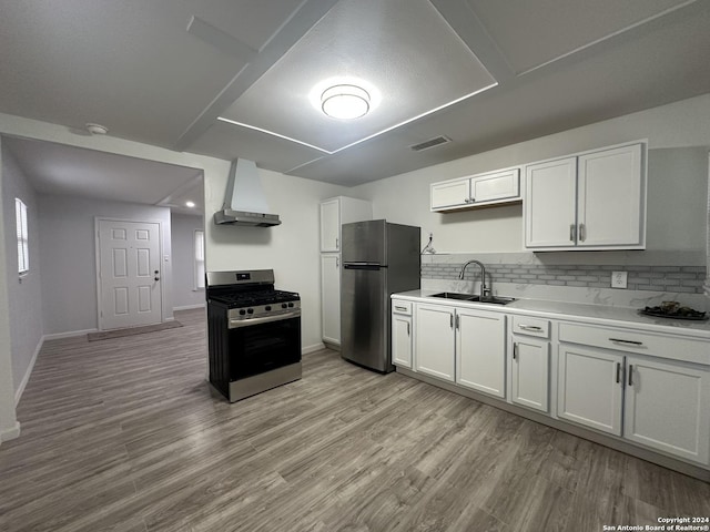 kitchen with sink, wall chimney range hood, light hardwood / wood-style flooring, white cabinets, and appliances with stainless steel finishes