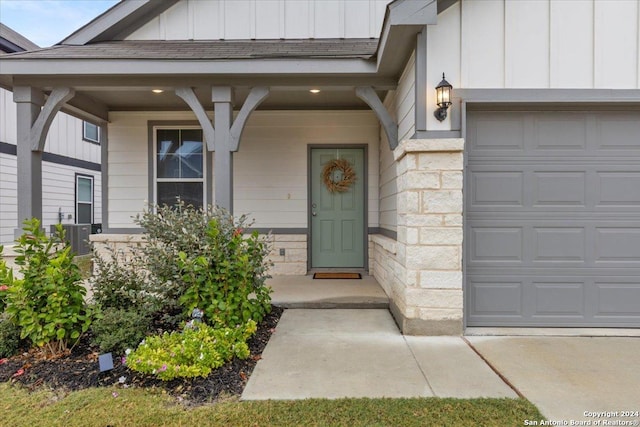 entrance to property featuring a garage and cooling unit