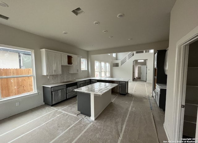 kitchen with gray cabinetry, backsplash, white cabinetry, a kitchen island, and kitchen peninsula