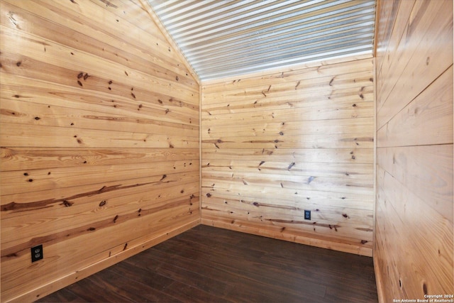 unfurnished room with wooden walls, dark wood-type flooring, and vaulted ceiling