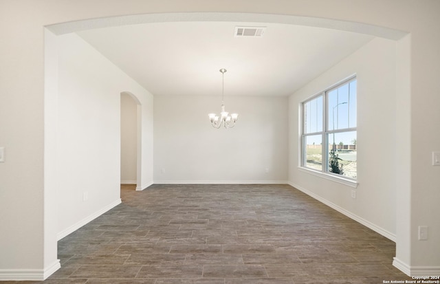 unfurnished dining area featuring a notable chandelier and dark hardwood / wood-style floors