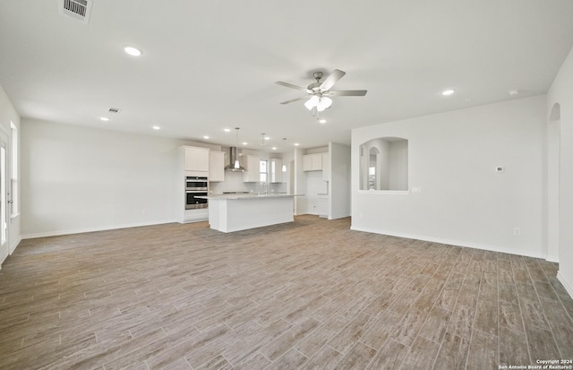 unfurnished living room with ceiling fan and light hardwood / wood-style flooring