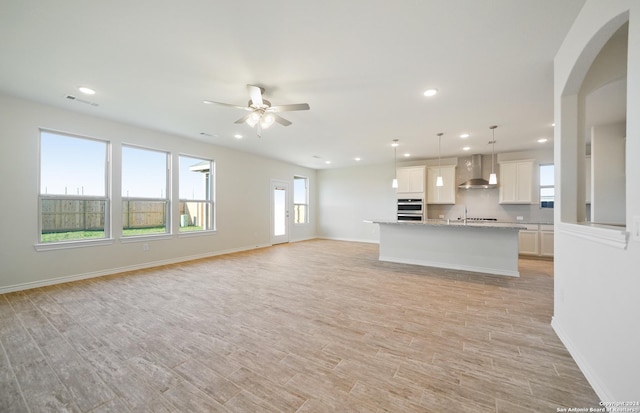 unfurnished living room featuring ceiling fan, light hardwood / wood-style flooring, and sink