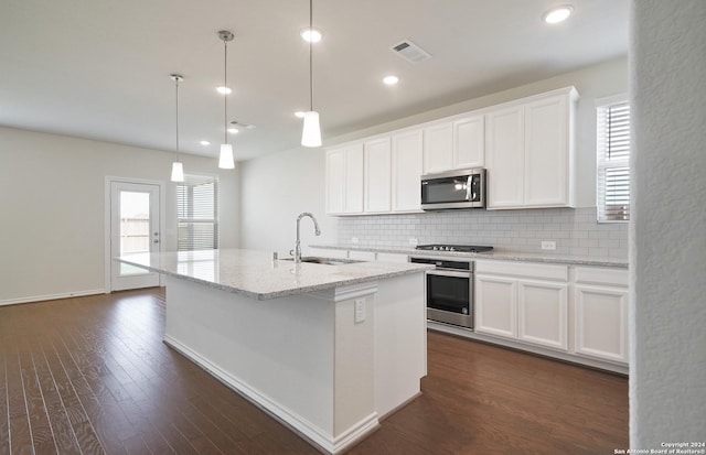 kitchen with white cabinetry, hanging light fixtures, dark hardwood / wood-style floors, an island with sink, and appliances with stainless steel finishes