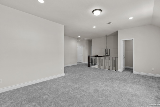 spare room featuring a chandelier, carpet floors, and vaulted ceiling