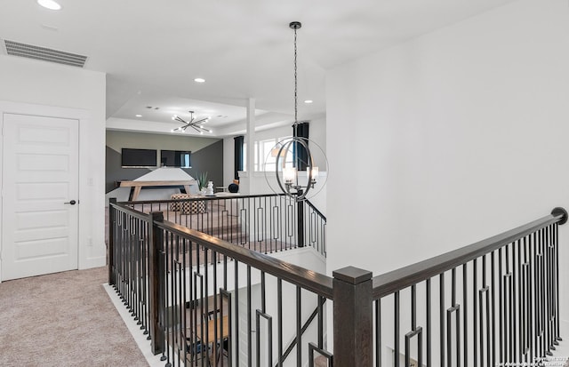 hall featuring light carpet and an inviting chandelier