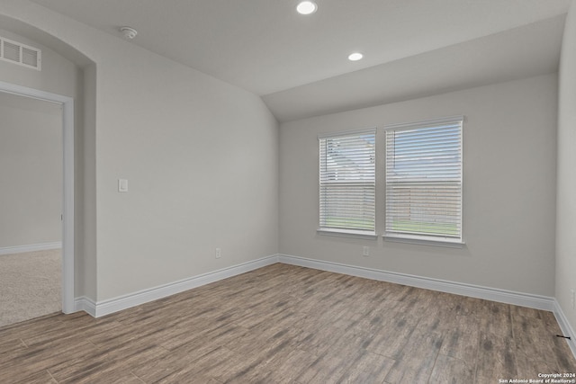 spare room featuring hardwood / wood-style floors and vaulted ceiling