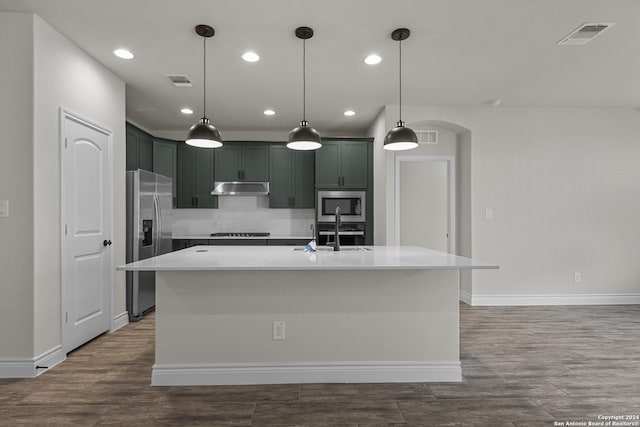 kitchen featuring stainless steel appliances, a kitchen island with sink, dark wood-type flooring, sink, and decorative light fixtures