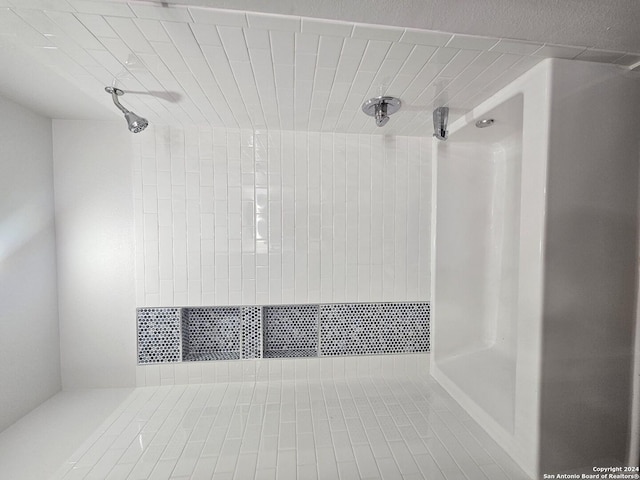 bathroom with tile patterned flooring and a tile shower