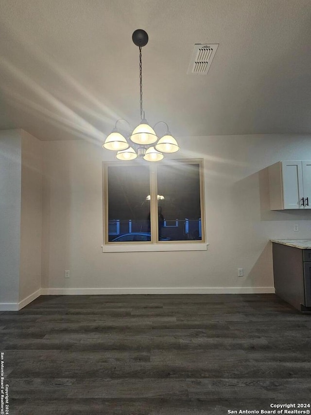 unfurnished dining area featuring dark hardwood / wood-style flooring and an inviting chandelier