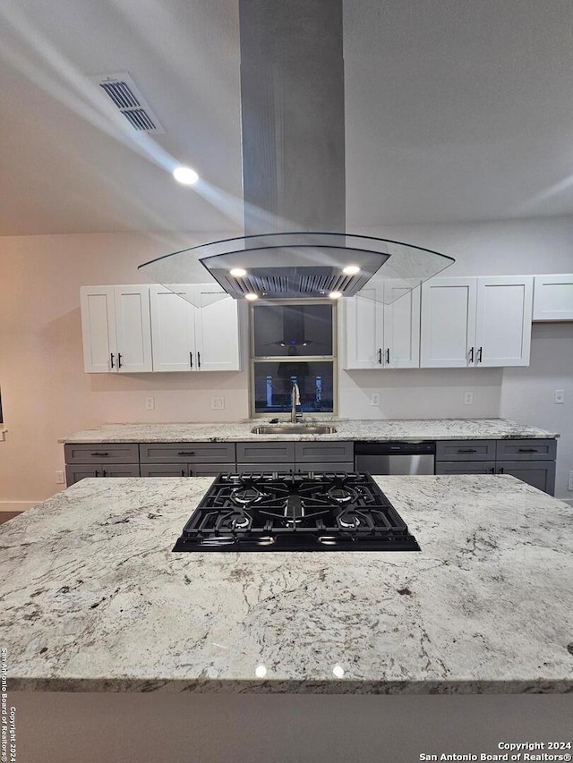 kitchen with light stone countertops, stainless steel dishwasher, island exhaust hood, white cabinets, and sink