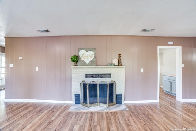 unfurnished living room featuring wood walls, light wood-type flooring, and a textured ceiling