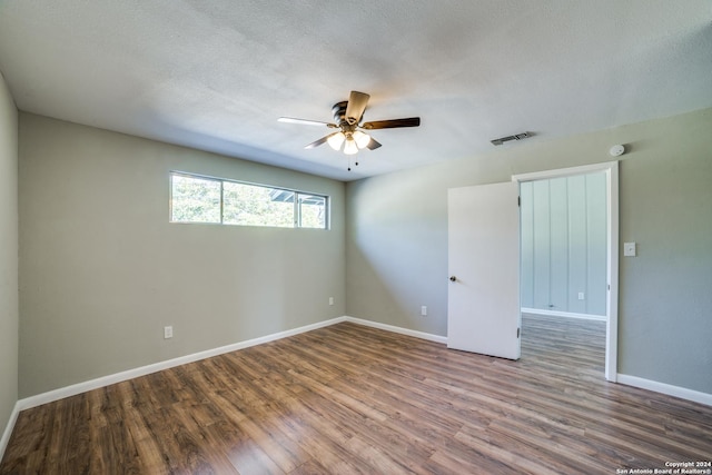 empty room with ceiling fan, wood-type flooring, and a textured ceiling