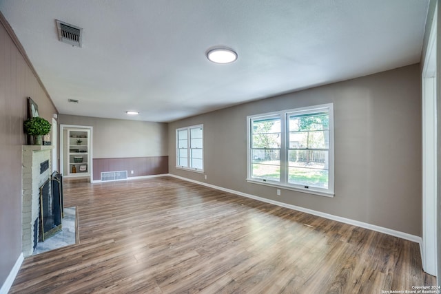 unfurnished living room with a fireplace, hardwood / wood-style floors, and built in shelves