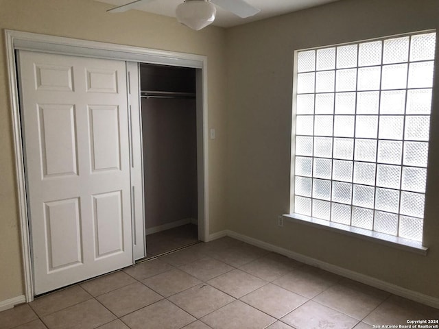 unfurnished bedroom with ceiling fan, light tile patterned floors, multiple windows, and a closet