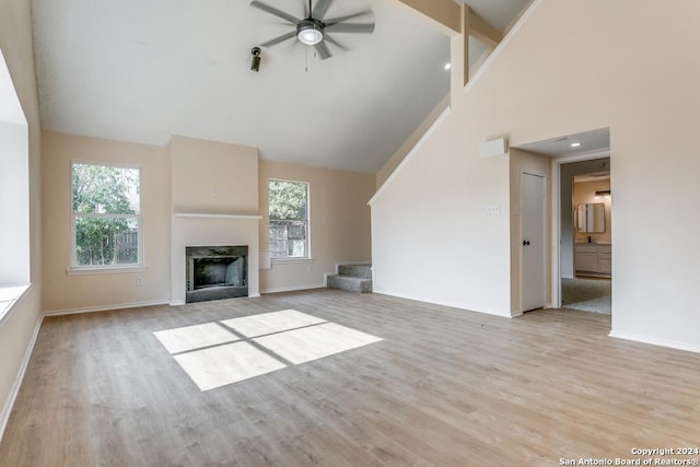 unfurnished living room featuring ceiling fan, high vaulted ceiling, and light wood-type flooring