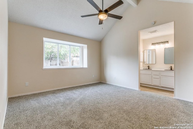 unfurnished bedroom featuring beam ceiling, connected bathroom, ceiling fan, high vaulted ceiling, and light colored carpet