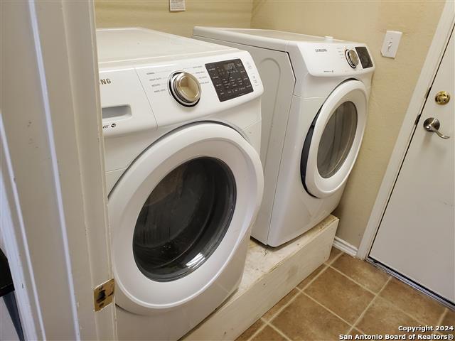 washroom with washing machine and clothes dryer and tile patterned floors