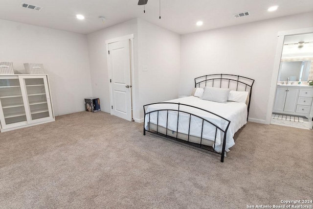 bedroom with light colored carpet, ensuite bath, and ceiling fan