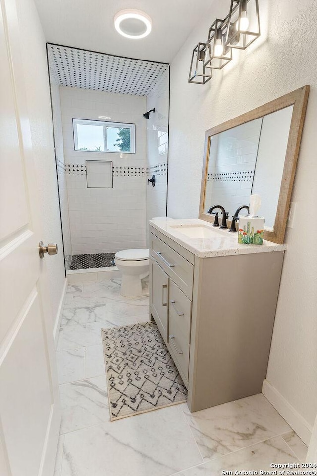 bathroom featuring vanity, toilet, and tiled shower