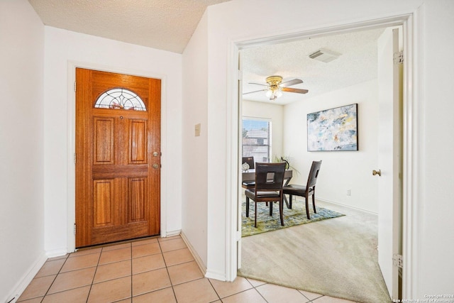 carpeted entryway with ceiling fan and a textured ceiling