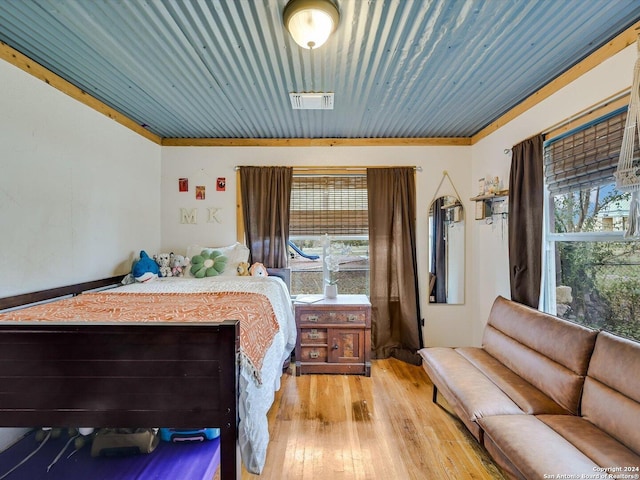 bedroom with light hardwood / wood-style floors, crown molding, and multiple windows