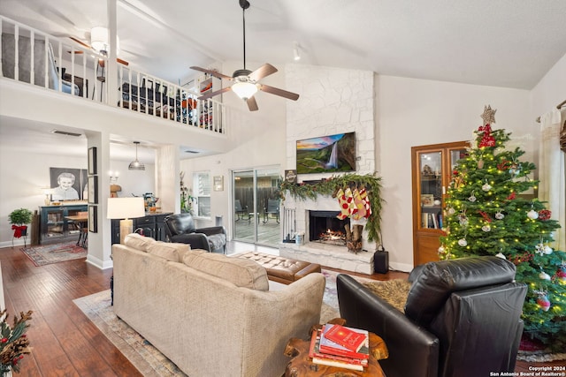 living room featuring a stone fireplace, ceiling fan, high vaulted ceiling, and dark wood-type flooring