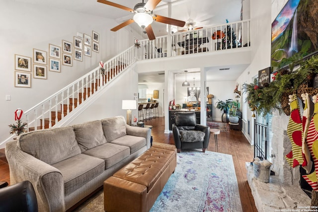 living room with hardwood / wood-style flooring, ceiling fan with notable chandelier, and high vaulted ceiling