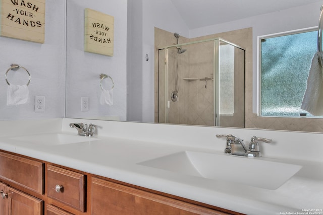 bathroom with plenty of natural light, vanity, vaulted ceiling, and walk in shower