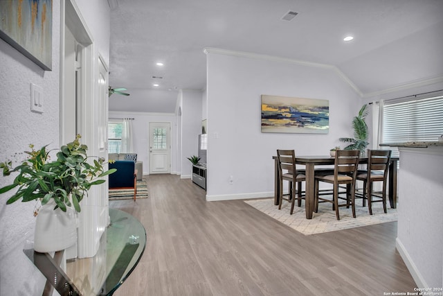 dining area featuring ceiling fan, ornamental molding, vaulted ceiling, and light wood-type flooring