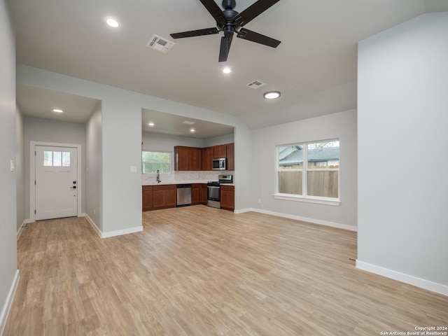 unfurnished living room featuring plenty of natural light, ceiling fan, light wood-type flooring, and sink