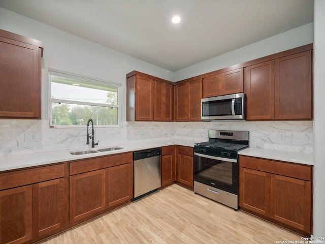 kitchen with decorative backsplash, appliances with stainless steel finishes, light hardwood / wood-style floors, and sink