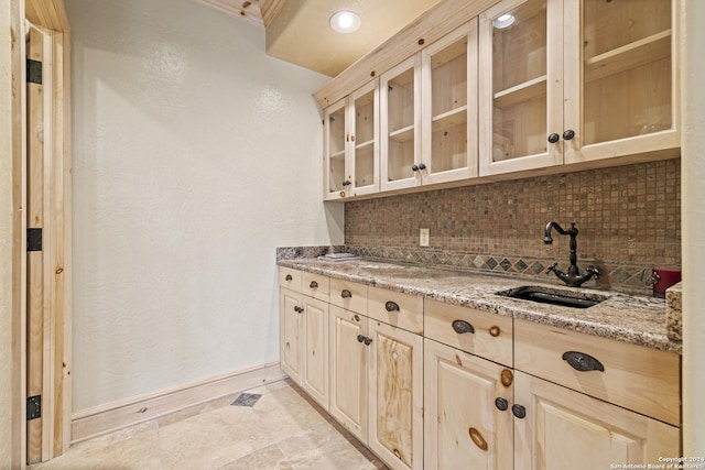 694 Scenic Cir, Pipe Creek, TX 78063 - kitchen featuring tasteful backsplash, light stone countertops, light brown cabinetry, glass insert cabinets, and a textured wall
