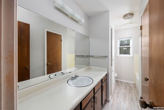 bathroom with a tub, vanity, wood-type flooring, and toilet